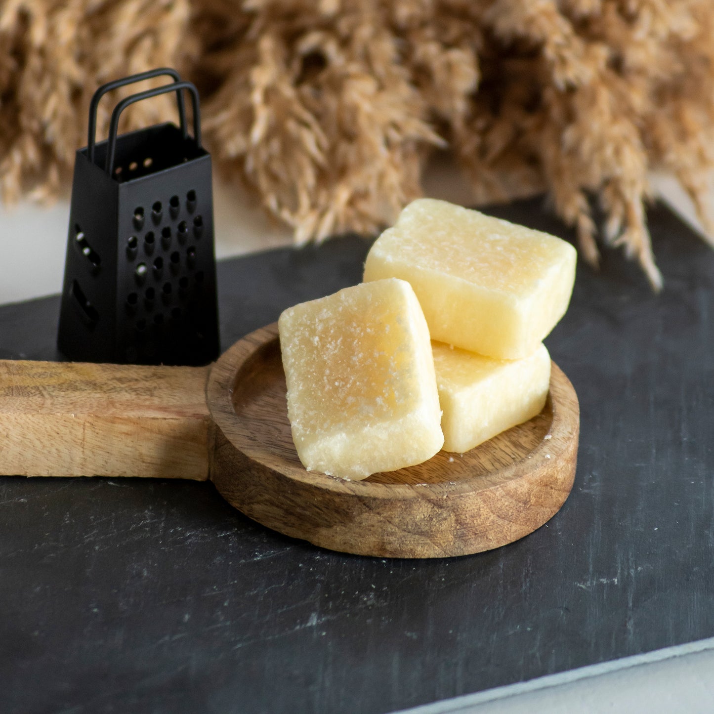 Drie vanille amberblokjes op houten plankje met rasp ernaast