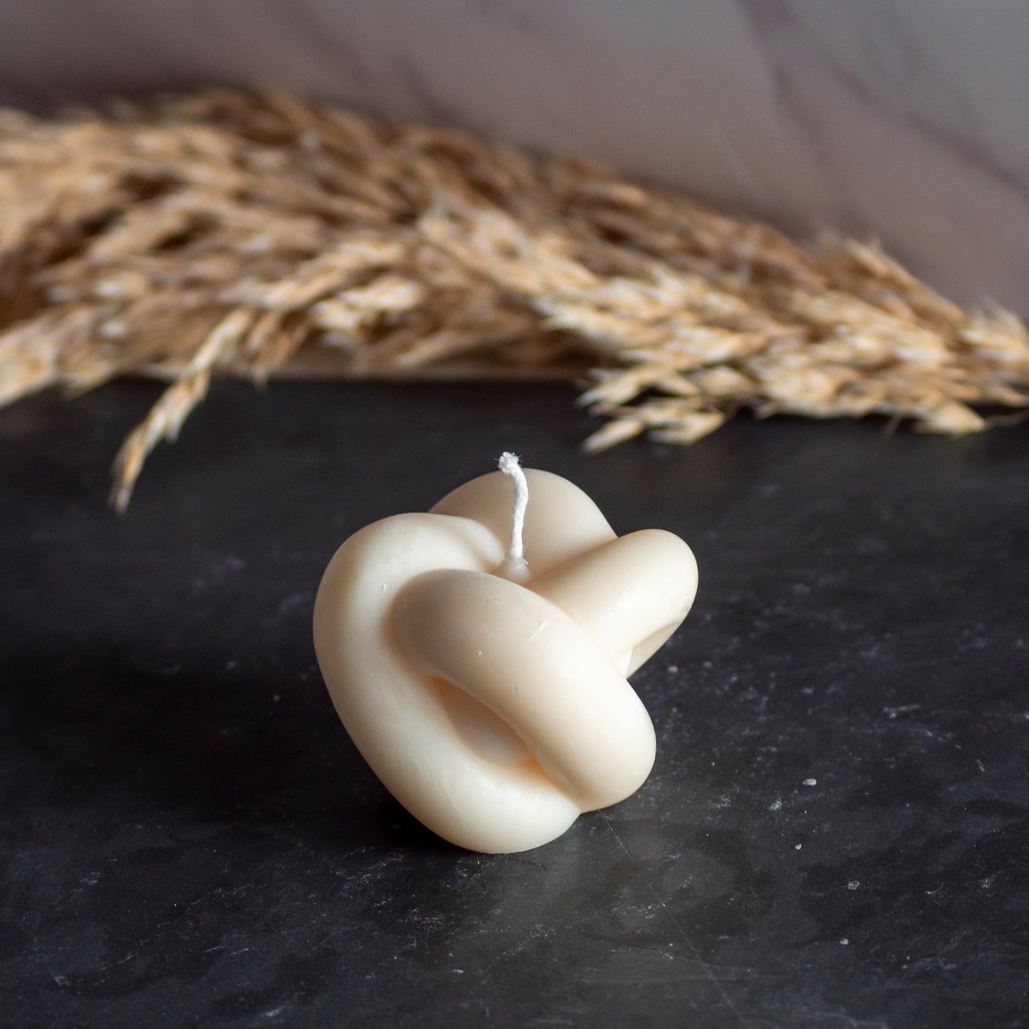 Beigekleurige Soft Knut kaars in rustige, natuurlijke setting