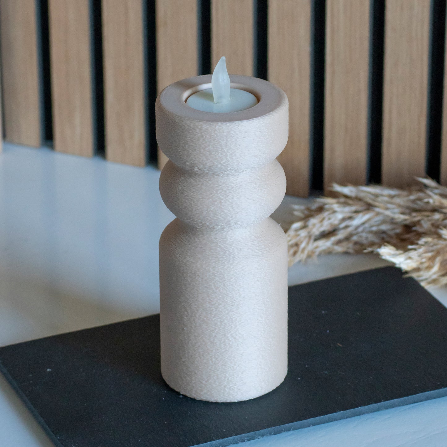 Waxinelichthouder als kandelaar in kleur latte voor LED lichtjes op witte tafel en houten achtergrond