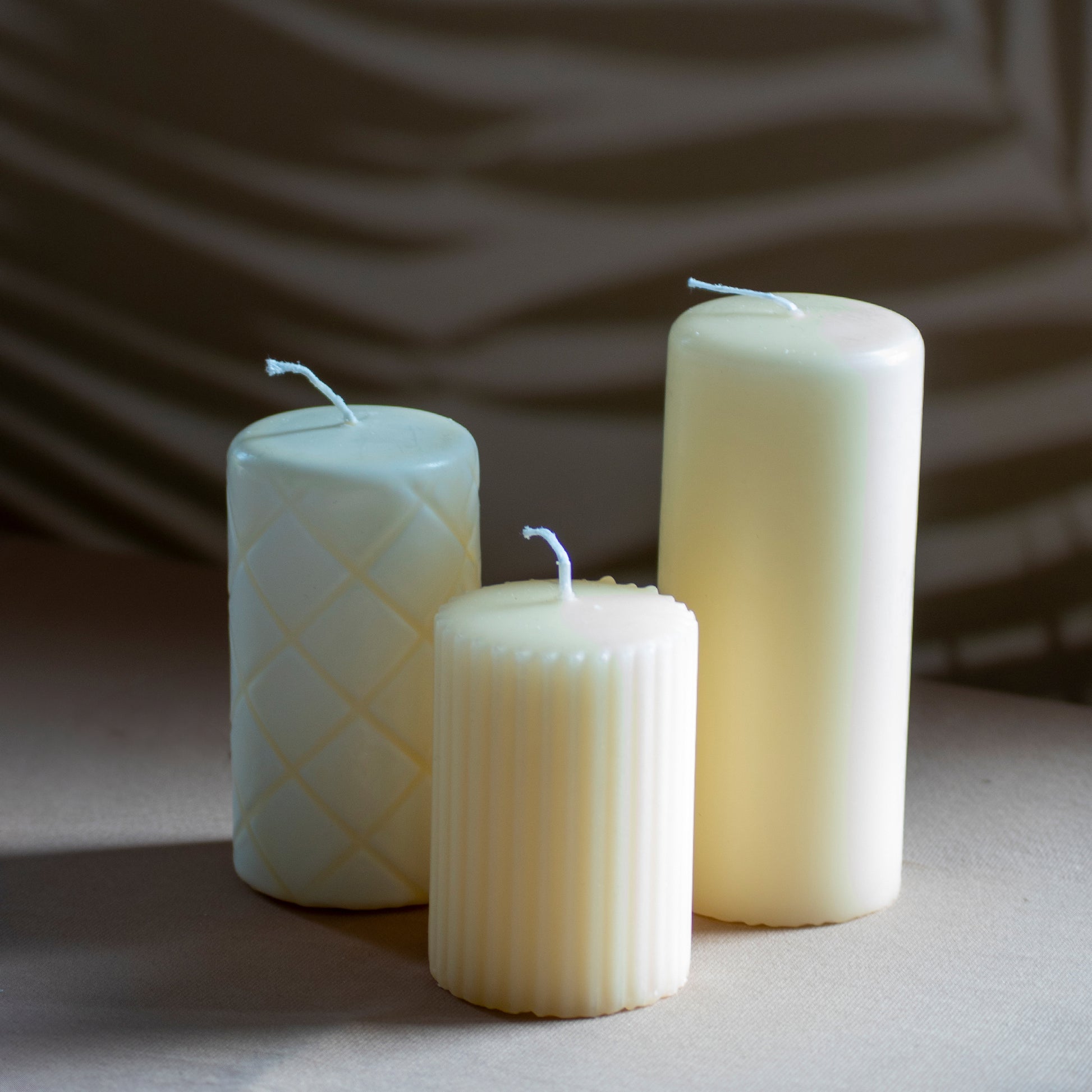 Set Ami met drie kaarsen in beige op neutrale achtergrond en rustige lichtval