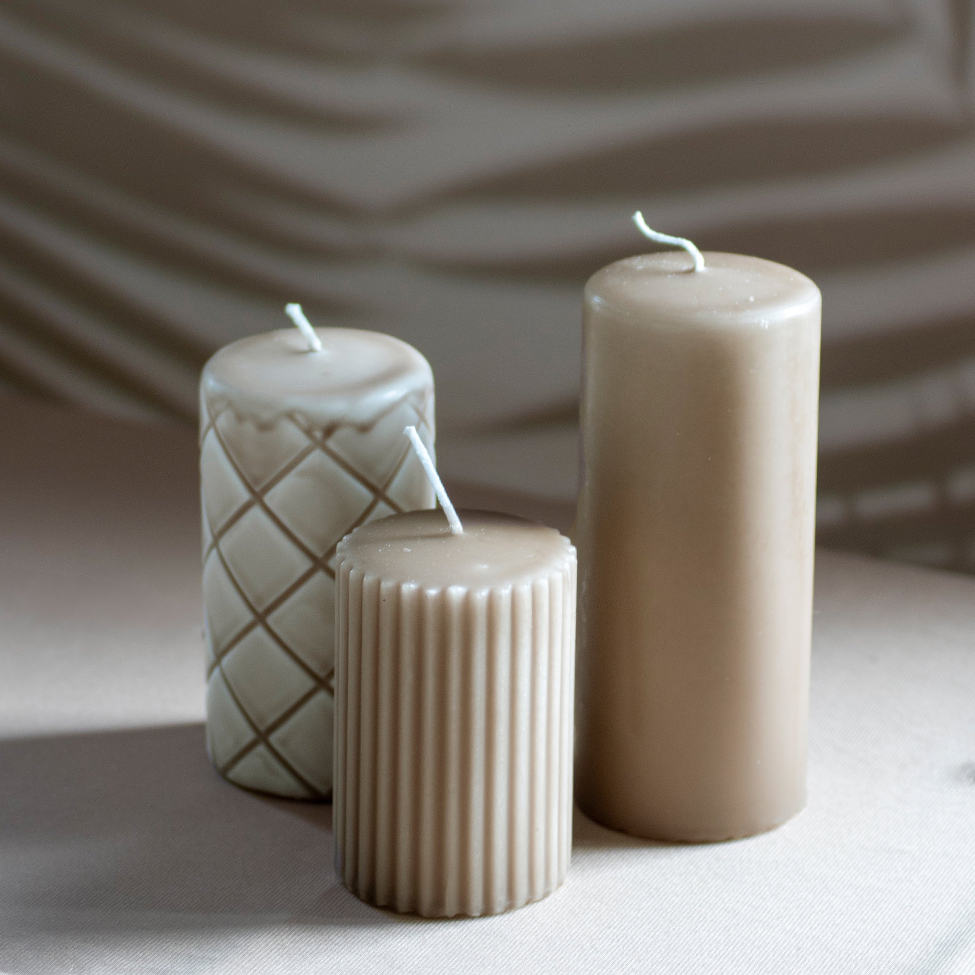 Set Ami met drie kaarsen in cappuccino op neutrale achtergrond en rustige lichtval