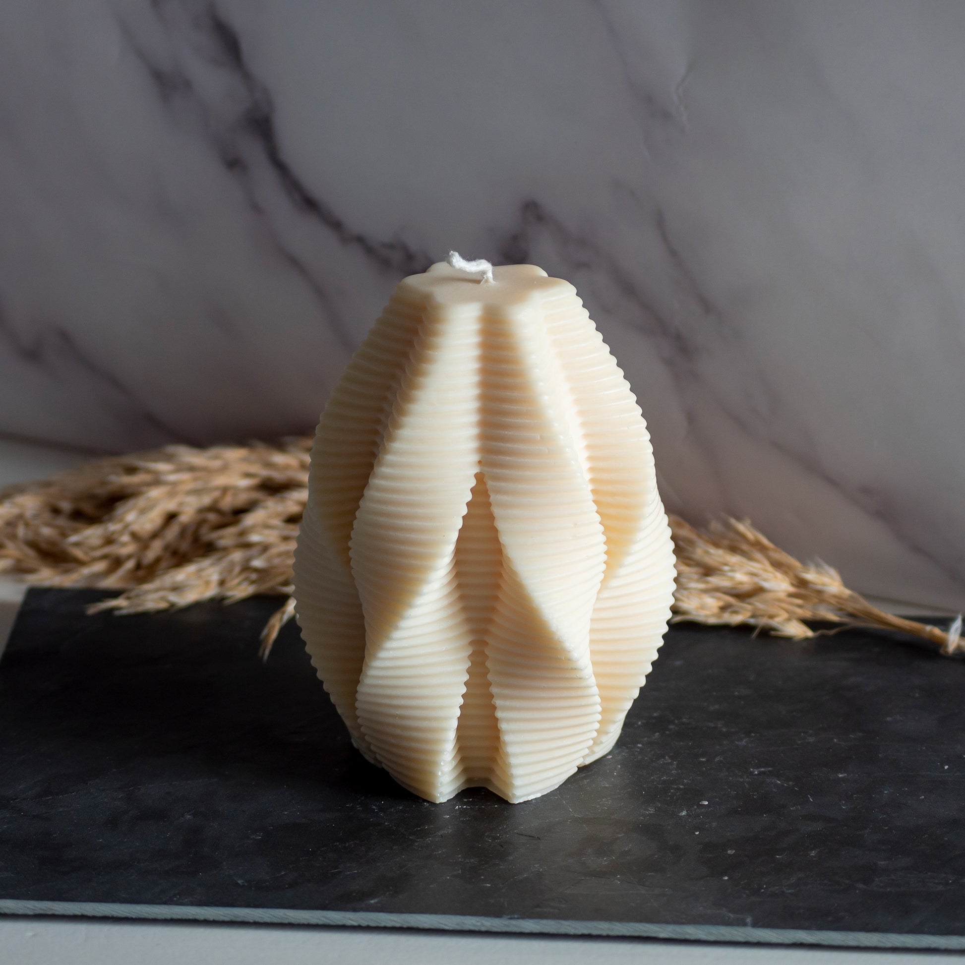 Beigekleurige Honey Fold kaars in rustige, natuurlijke setting