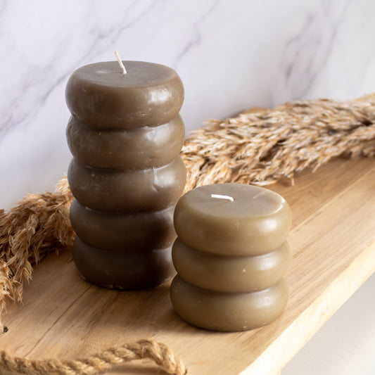 Hoge en lage ringelkaarsen in donkerbruine kleur op houten plank met tarwe als decoratie