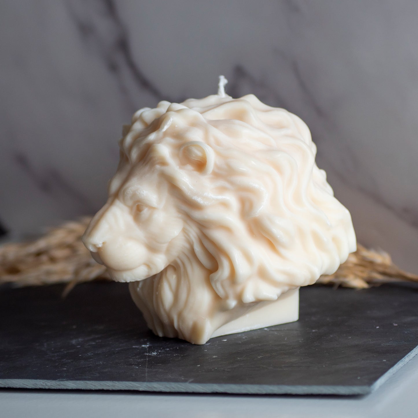 Beigekleurige Lion Light kaars in rustige, natuurlijke setting