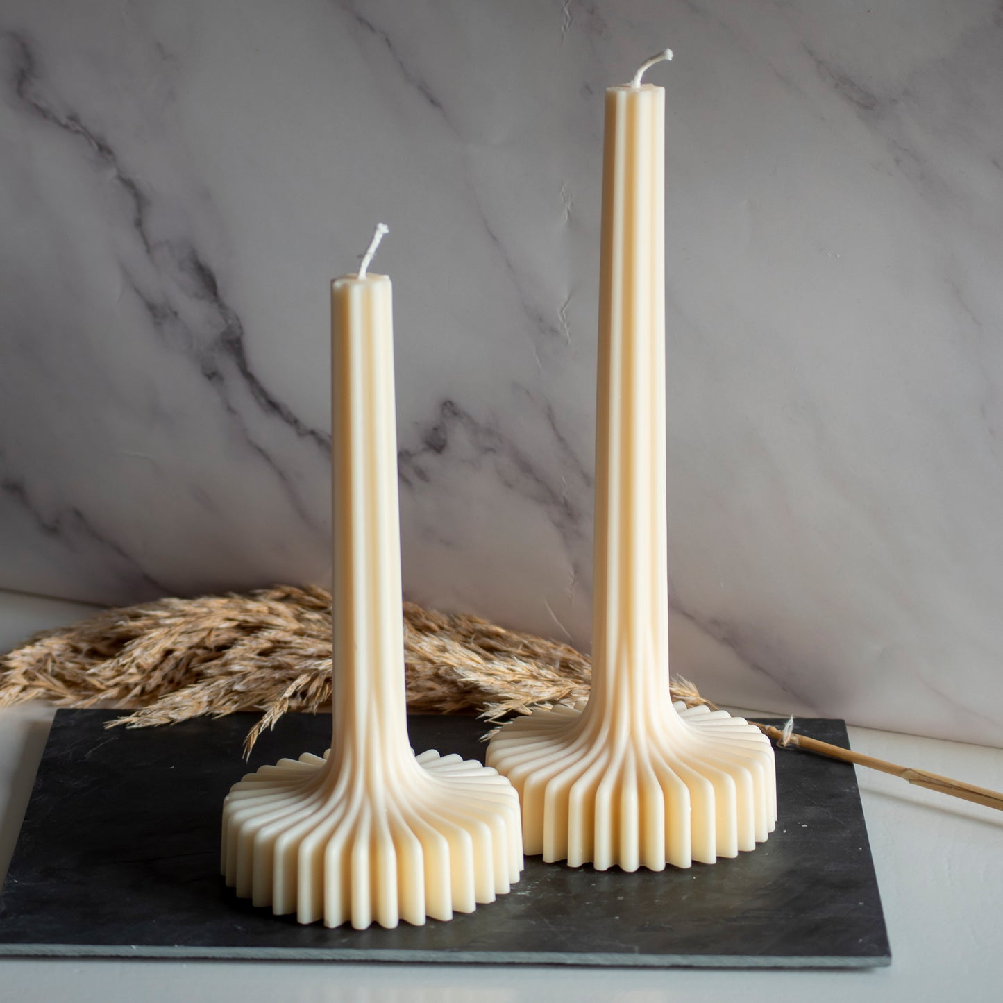 Twee beigekleurige Pleat Light kaarsen in rustige, natuurlijke setting