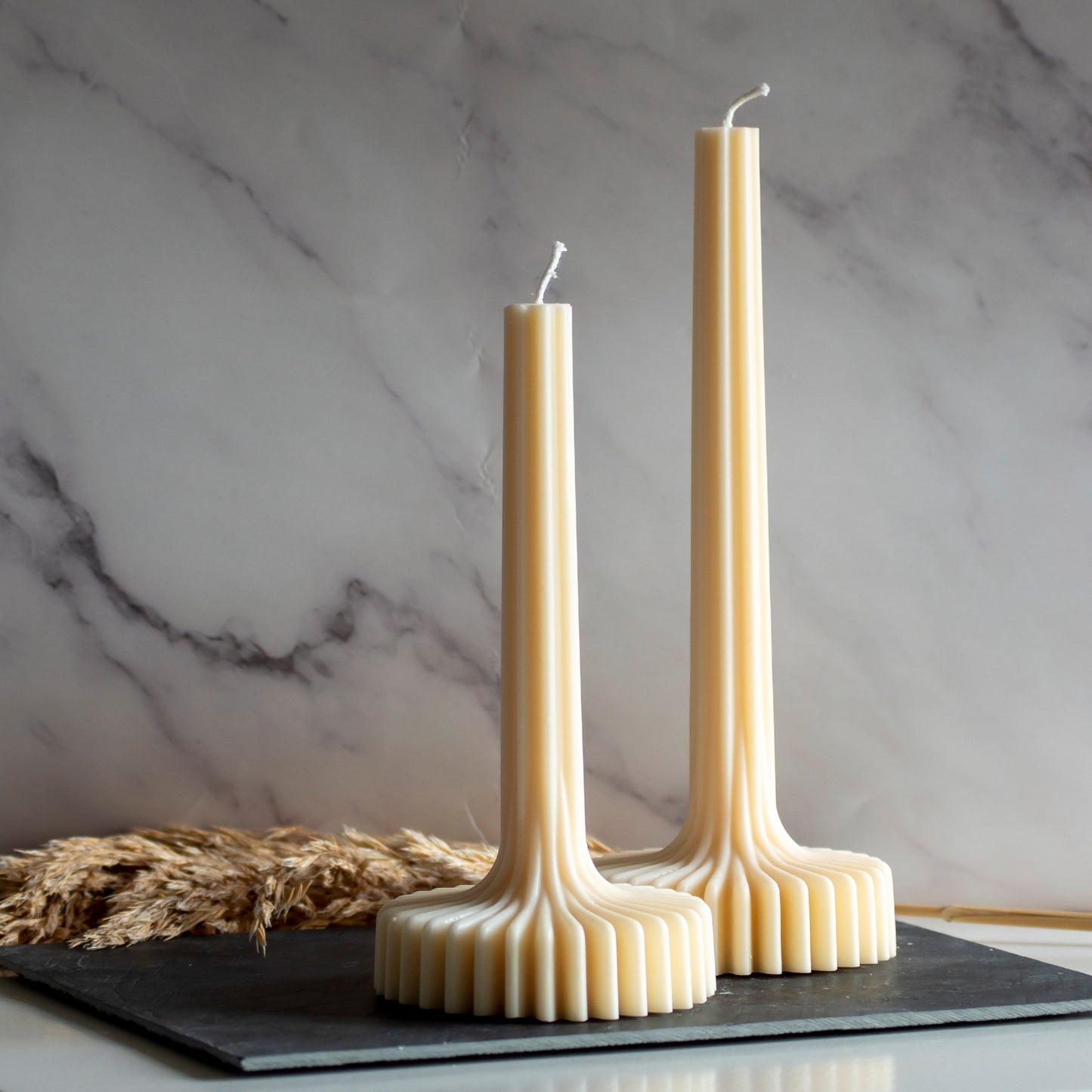 Twee beigekleurige Pleat Light kaarsen in rustige, natuurlijke setting