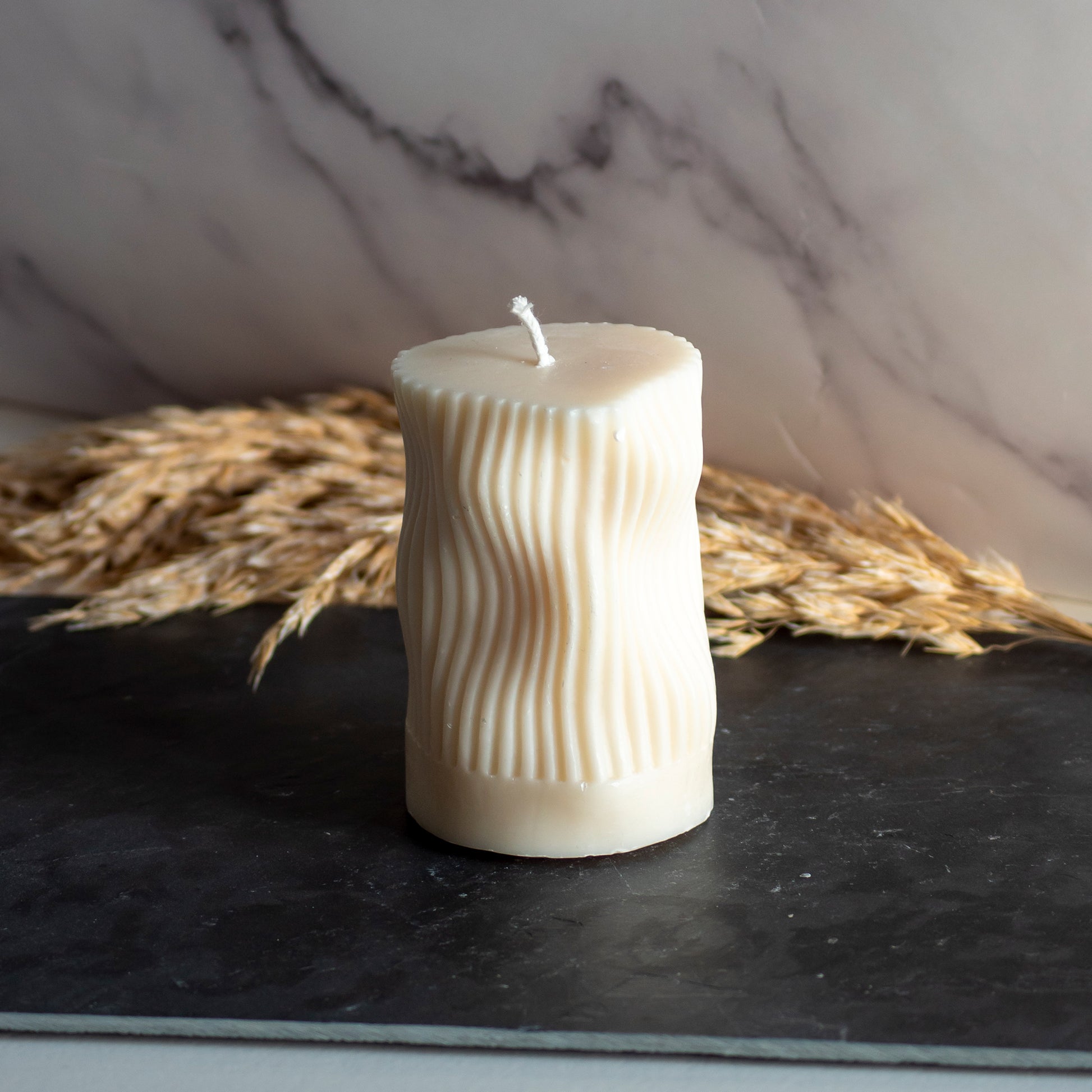 Beigekleurige Ripple Column kaars in rustige, natuurlijke setting