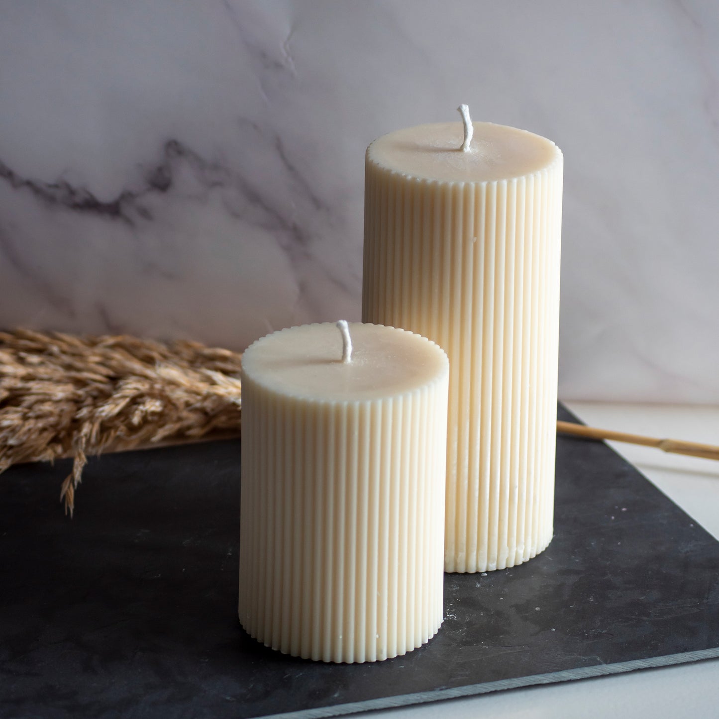 Twee beigekleurige Serene Column kaarsen in rustige, natuurlijke setting