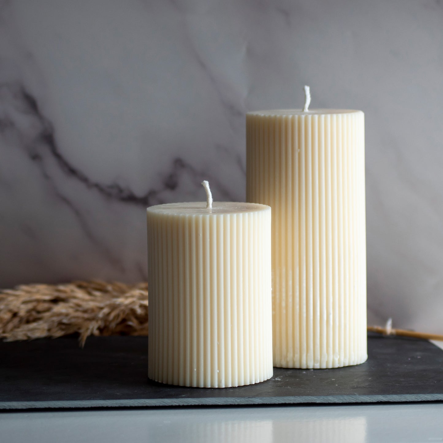 Twee beigekleurige Serene Column kaarsen in rustige, natuurlijke setting