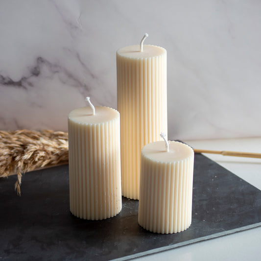 Drie beigekleurige Serene Column kaarsen in rustige, natuurlijke setting