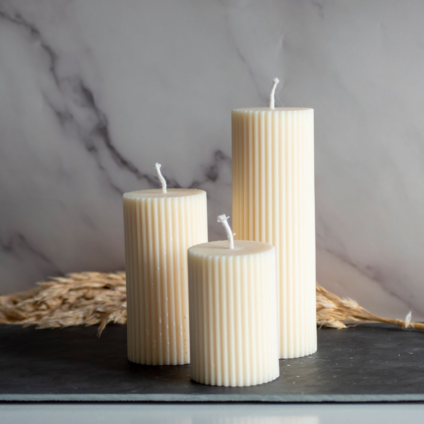 Drie beigekleurige Serene Column kaarsen in rustige, natuurlijke setting