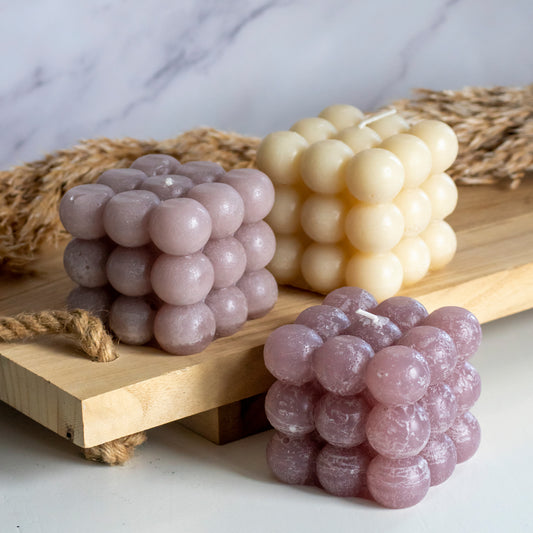 Bubbelkaarsen in diverse kleur op houten plank met pluimen als decoratie