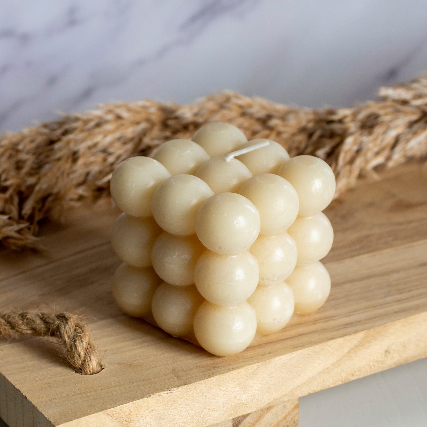 Bubbelkaars in kleur beige op houten plank met pluimen als decoratie