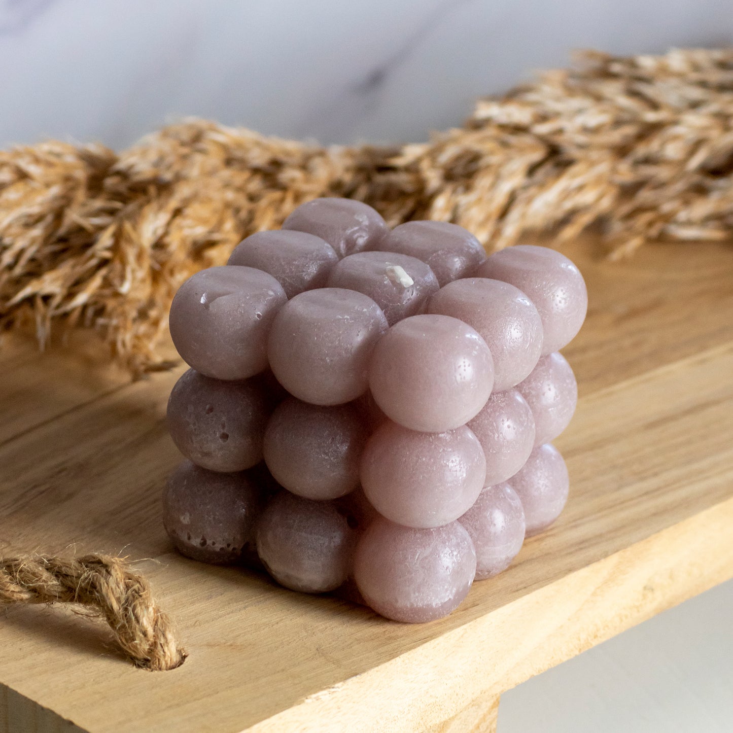 Bubbelkaars in kleur zachtroze op houten plank met pluimen als decoratie