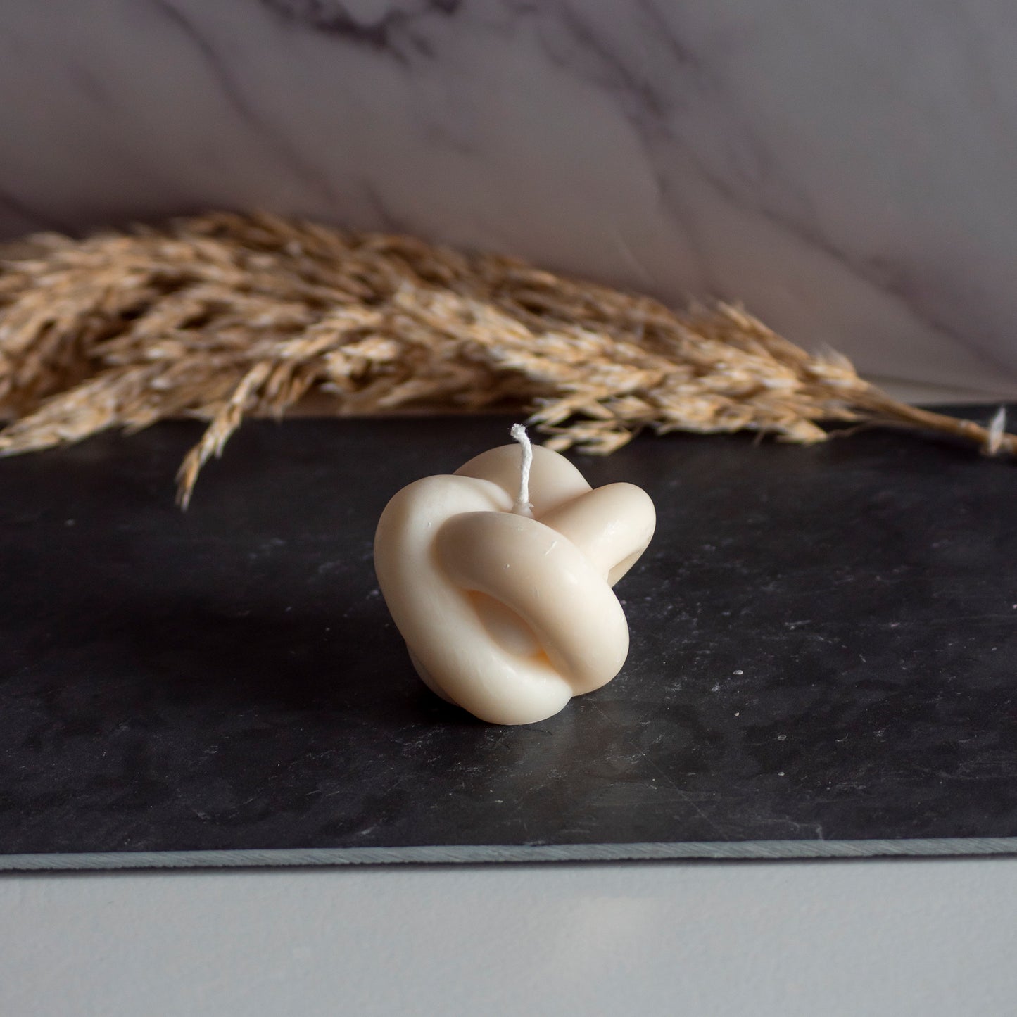 Beigekleurige Soft Knut kaars in rustige, natuurlijke setting