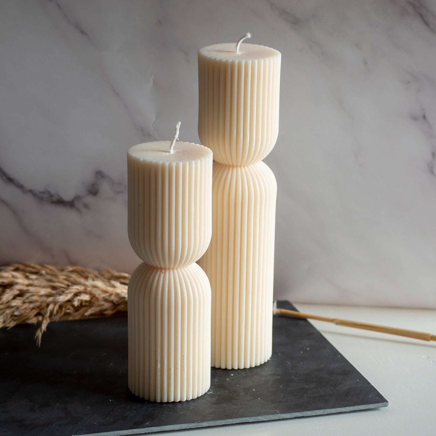 Twee beigekleurige Tall Grace kaarsen in rustige, natuurlijke setting