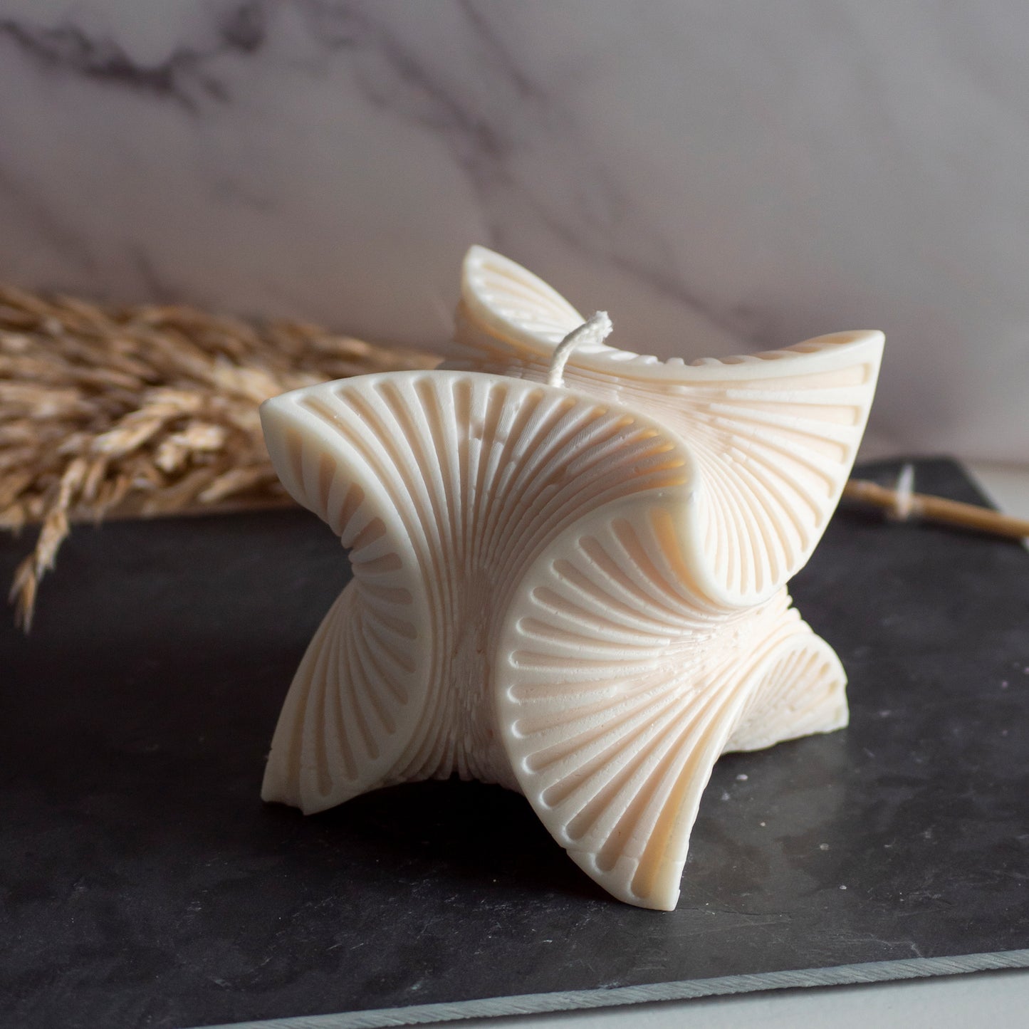 Beigekleurige Wave Harmony kaars in rustige, natuurlijke setting