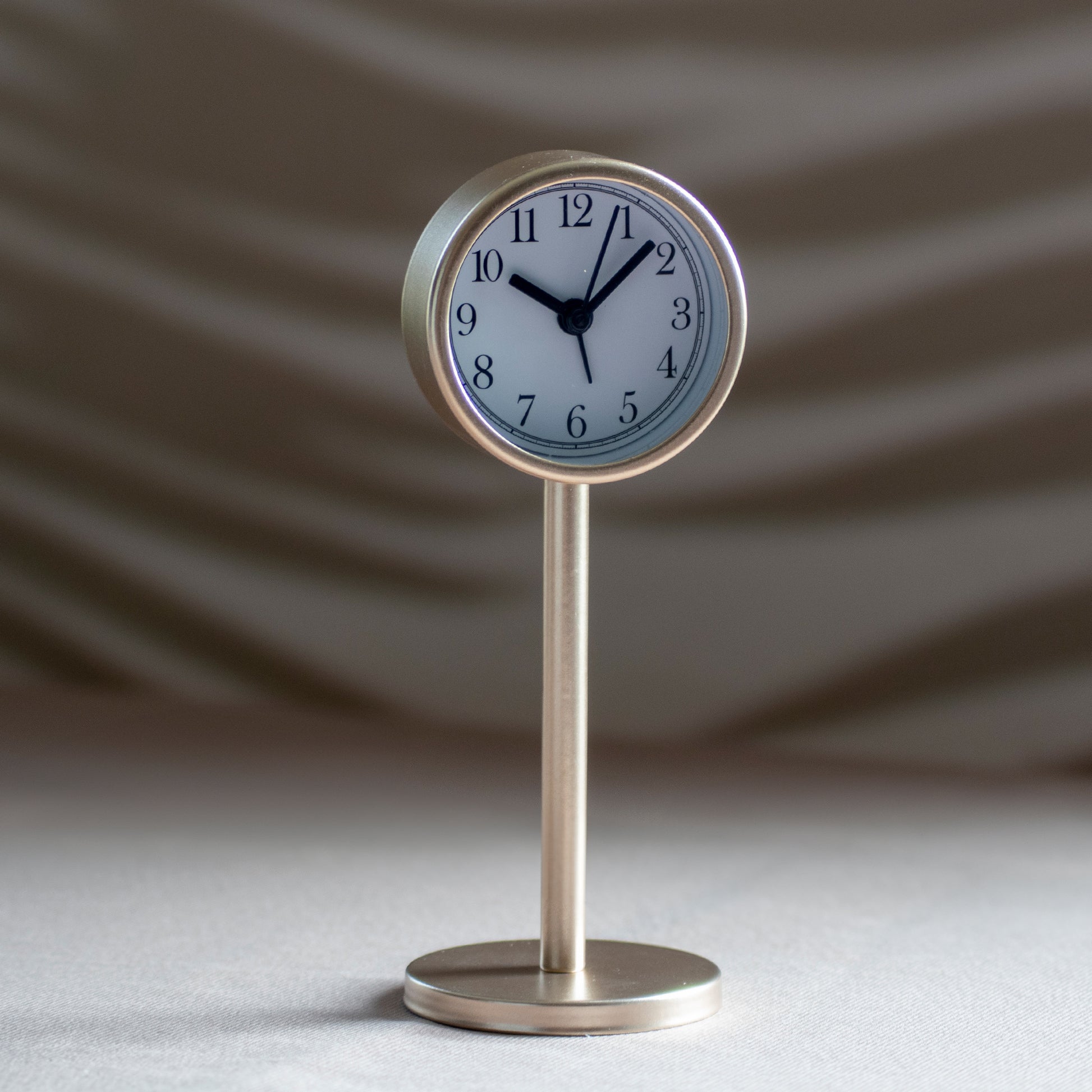 Tafelklokje Tiku in kleur goud op neutrale achtergrond en rustige lichtval