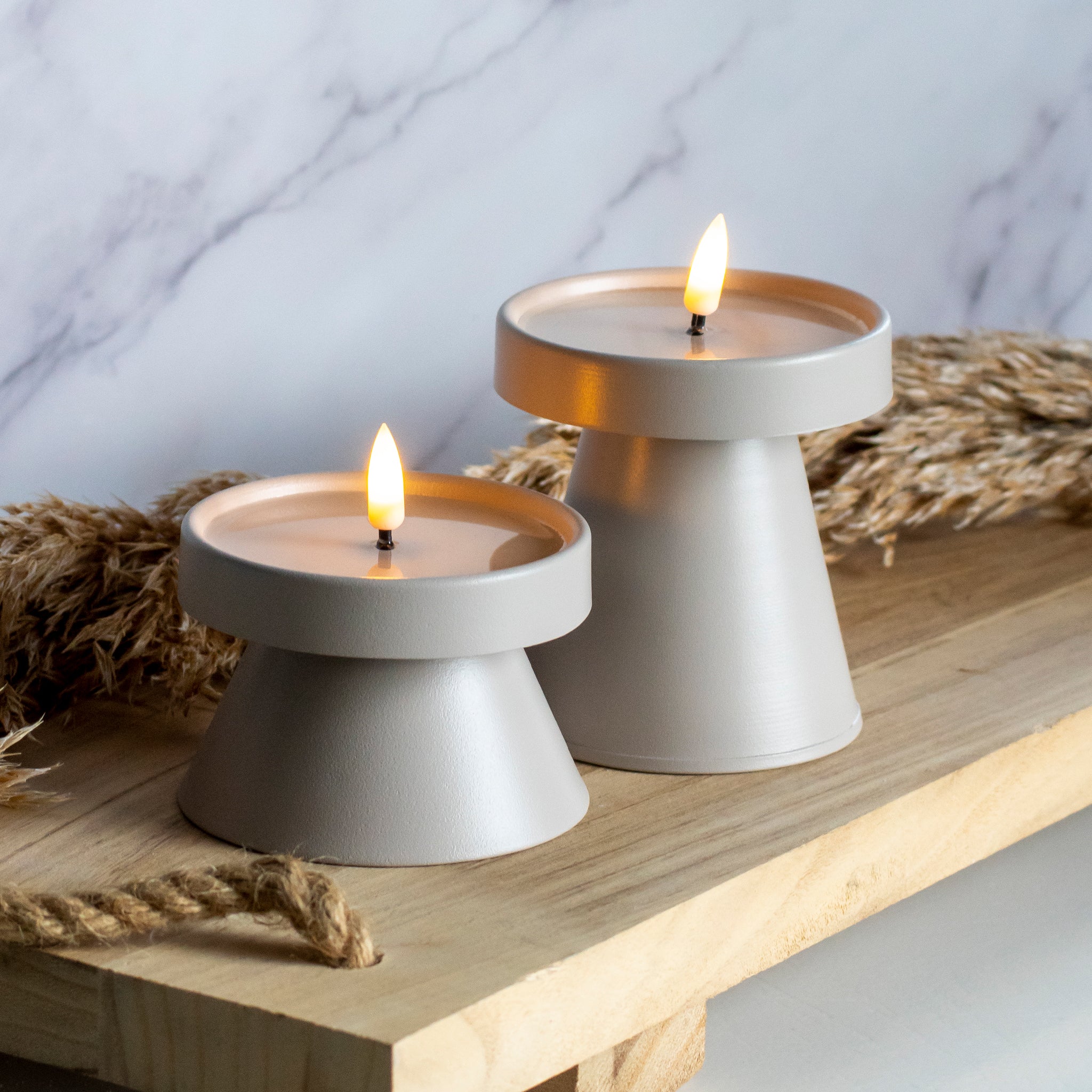 Hoge en lage LED kandelaar in taupe kleur op houten plank met tarwe decoratie