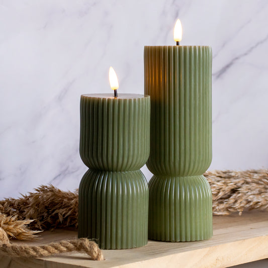 Hoge en lage LED kaarsen in groene kleur op houten plank met tarwe als decoratie