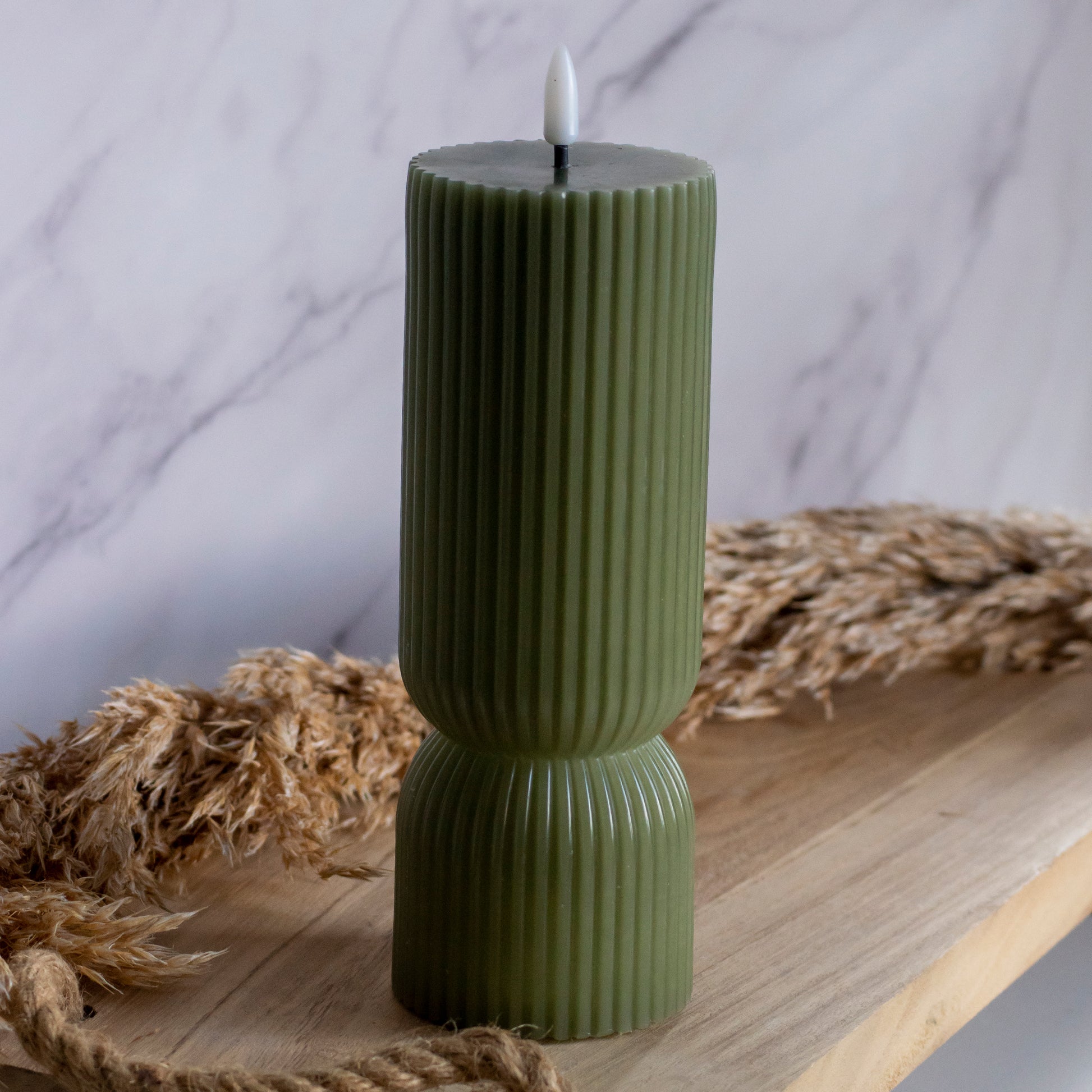 Hoge LED kaarsen in groene kleur op houten plank met tarwe als decoratie