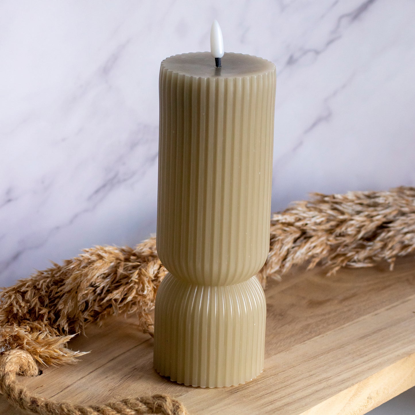 Hoge LED kaarsen in taupe kleur op houten plank met tarwe als decoratie