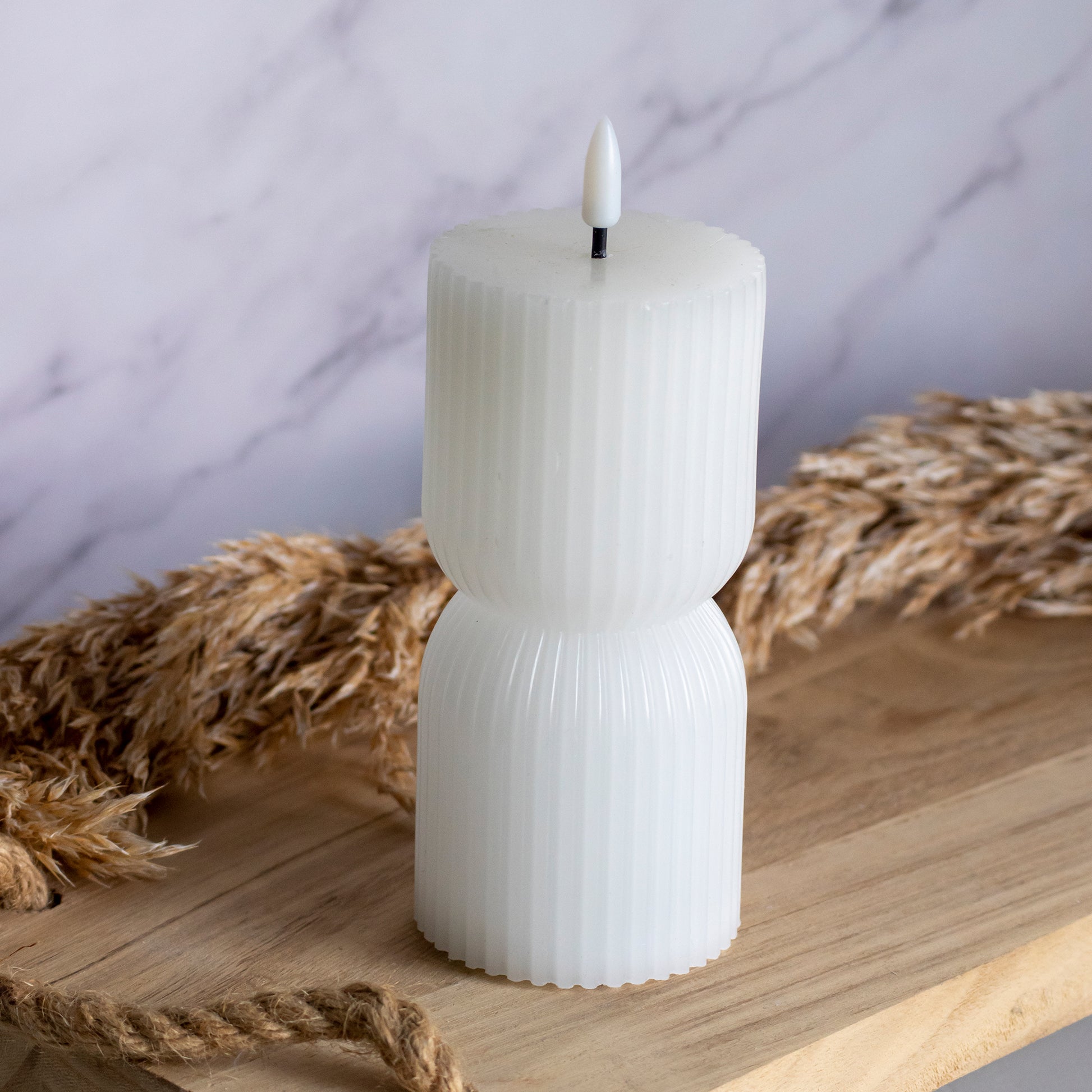Lage LED kaars in witte kleur op houten plank met tarwe als decoratie
