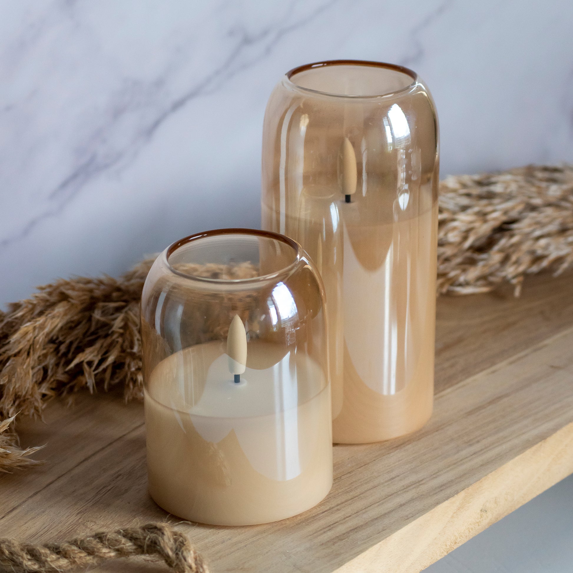 Hoge en lage LED kaarsen in glas in honingkleur op houten plank met tarwe als decoratie