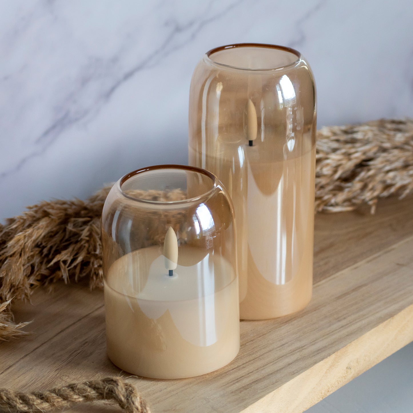 Hoge en lage LED kaarsen in glas in honingkleur op houten plank met tarwe als decoratie
