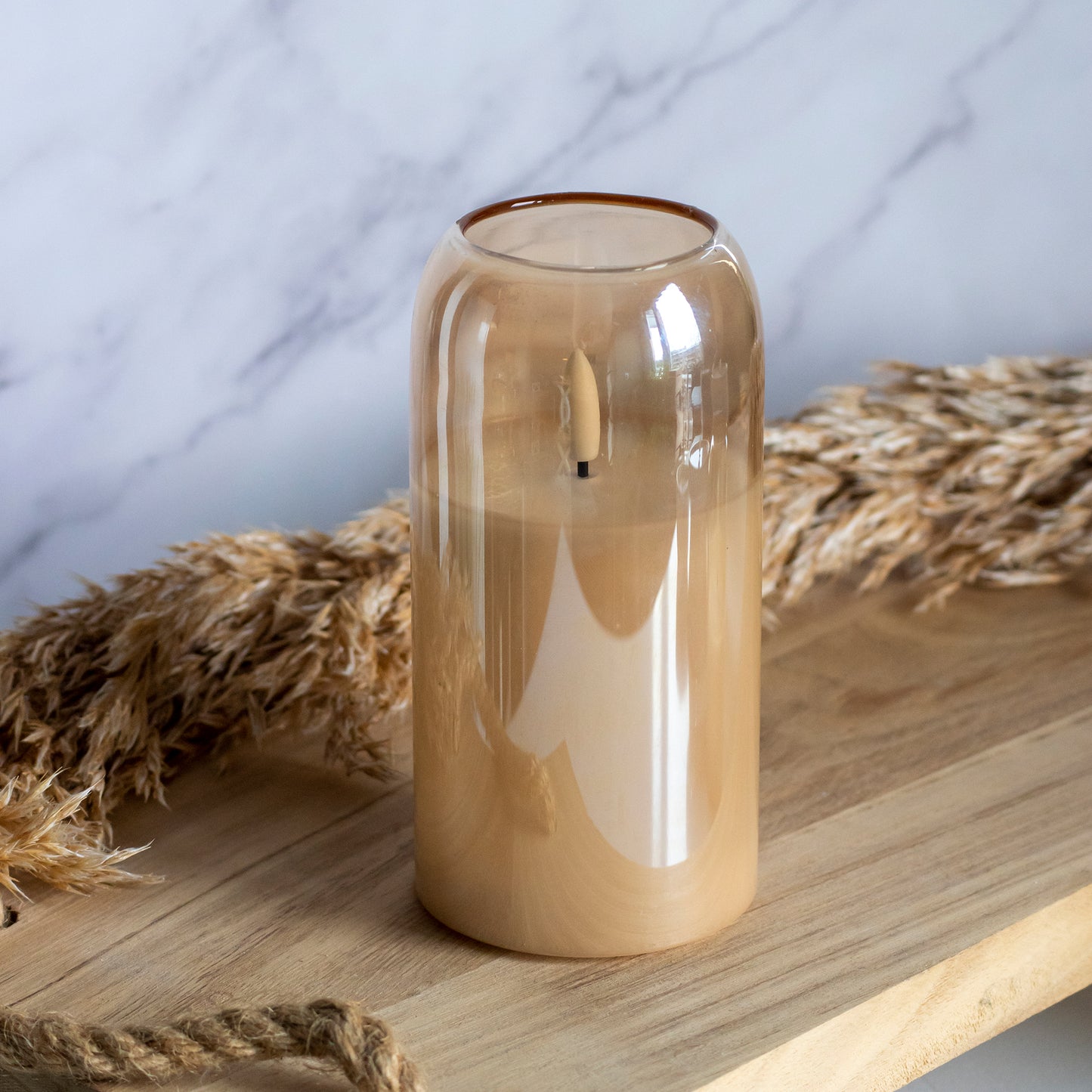 Hoge LED kaars in glas in honingkleur op houten plank met tarwe als decoratie