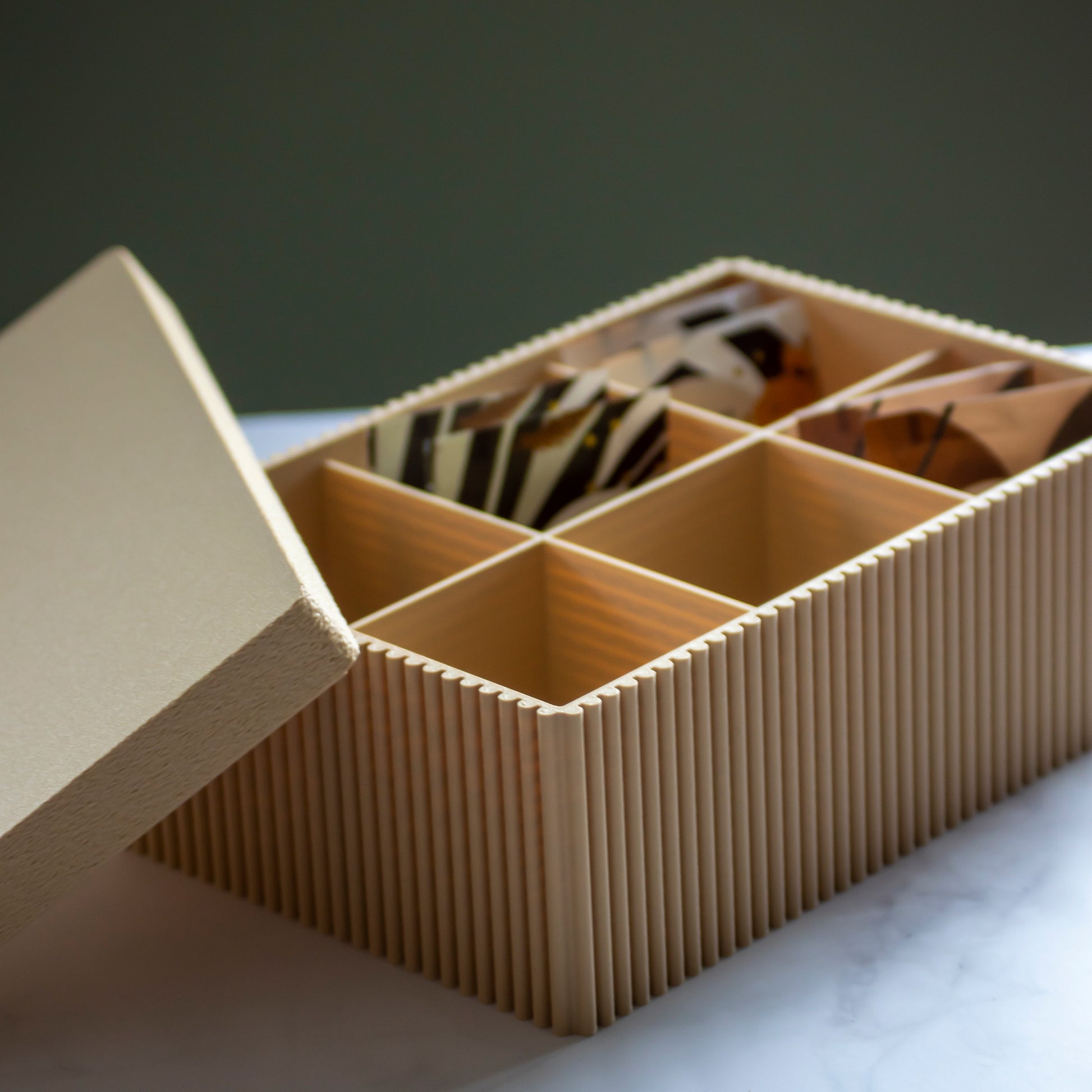 Theedoos Folda in kleur zandgeel op marmeren ondergrond en rustige lichtinval