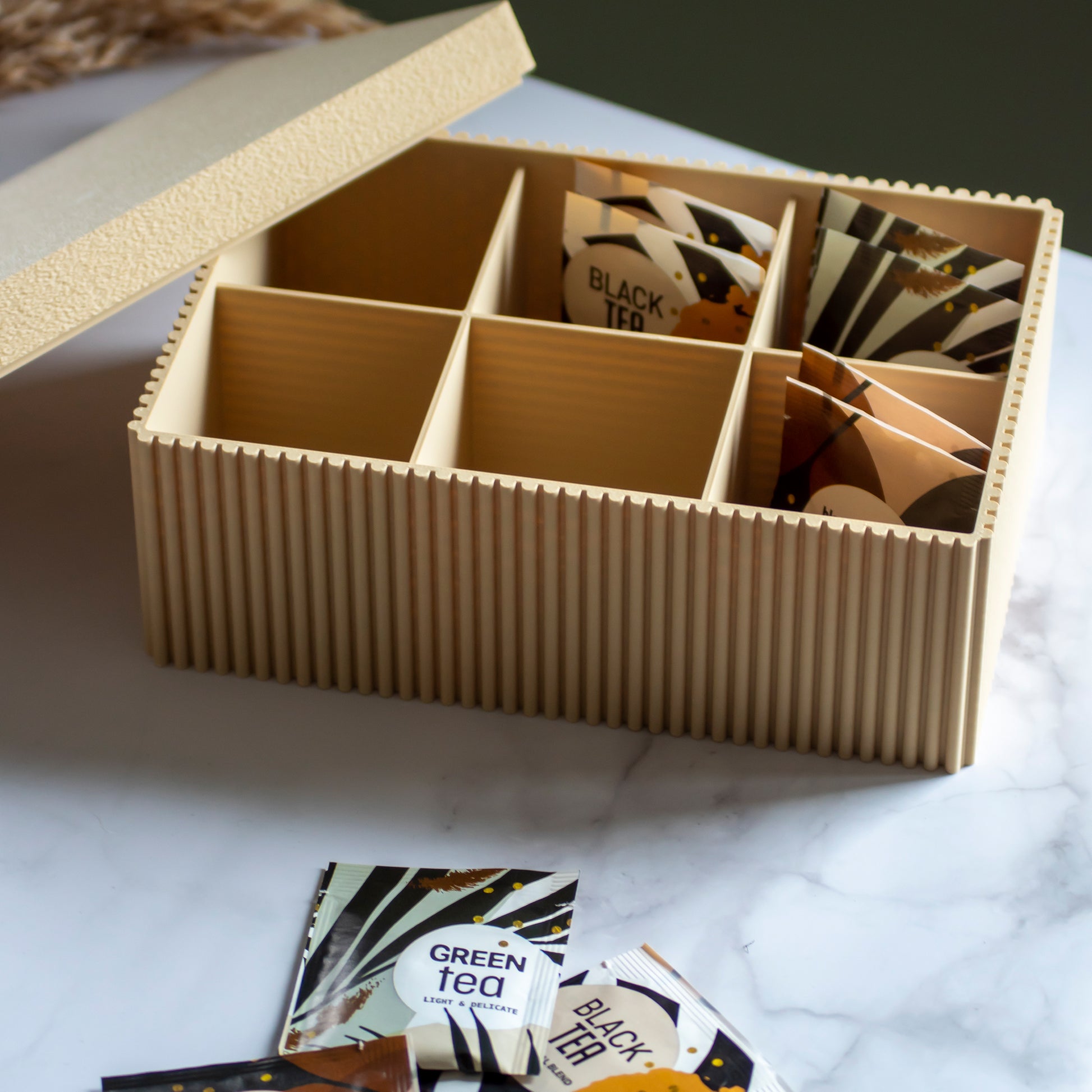 Theedoos Folda in kleur zandgeel op marmeren ondergrond en rustige lichtinval