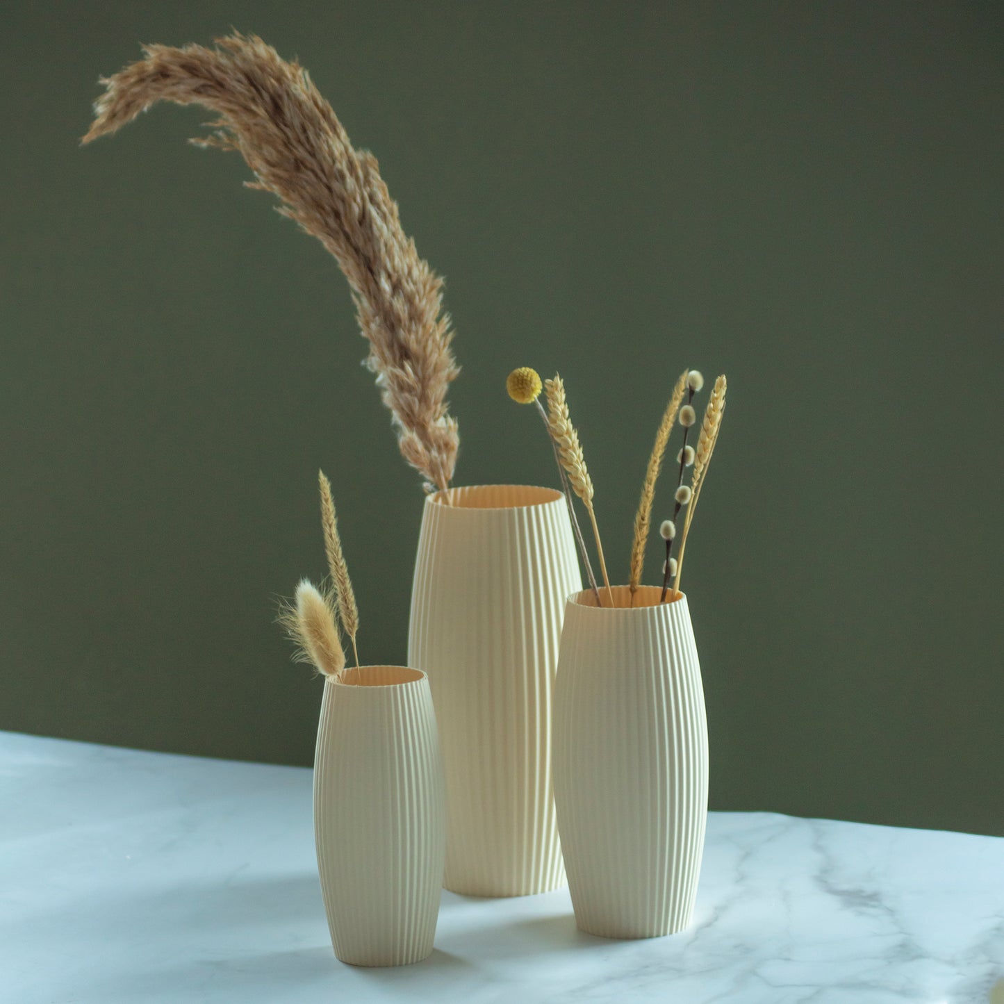 Beige vazen Nomi met droogbloemen op marmeren blad en groene achtergrond