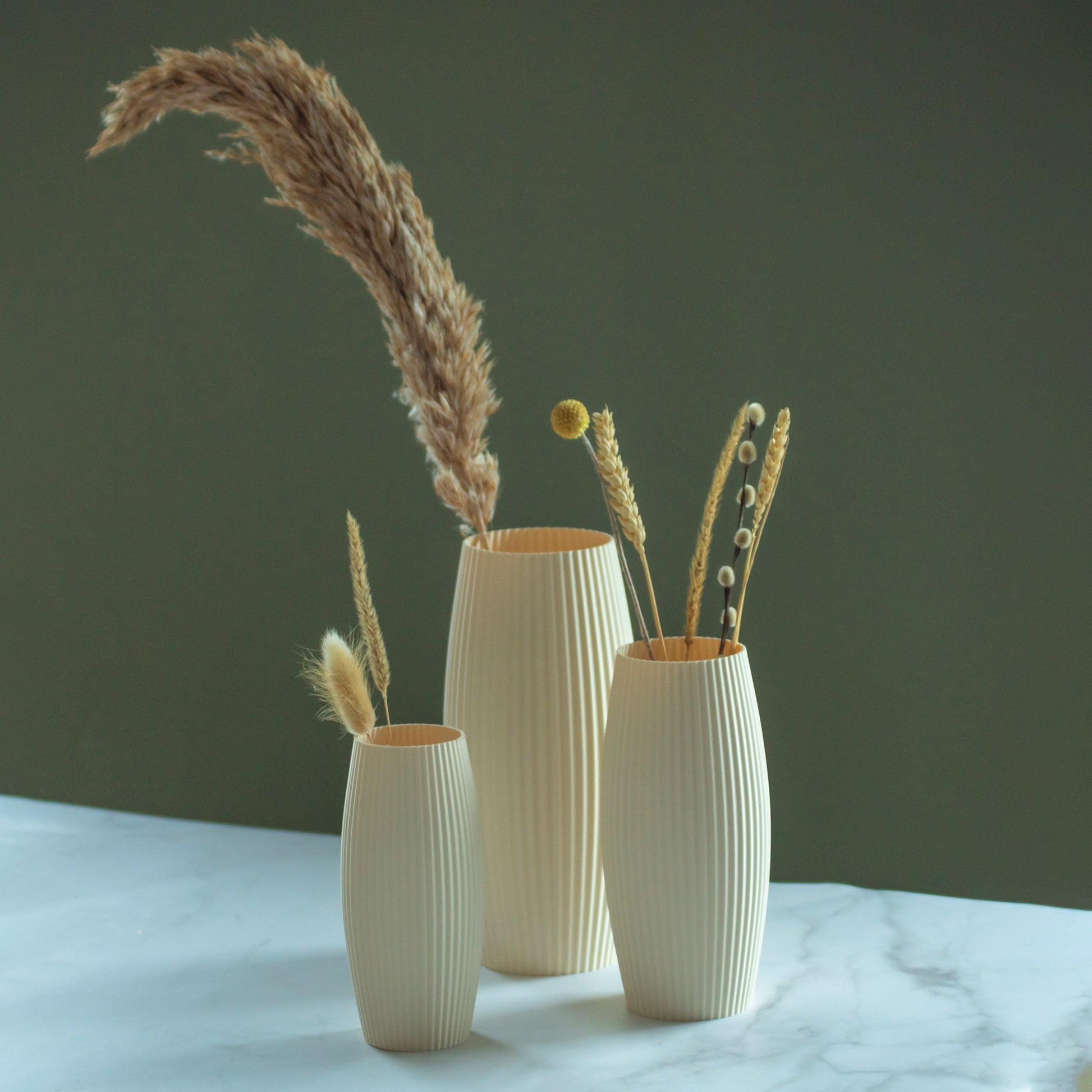 Beige vazen Nomi met droogbloemen op marmeren blad en groene achtergrond