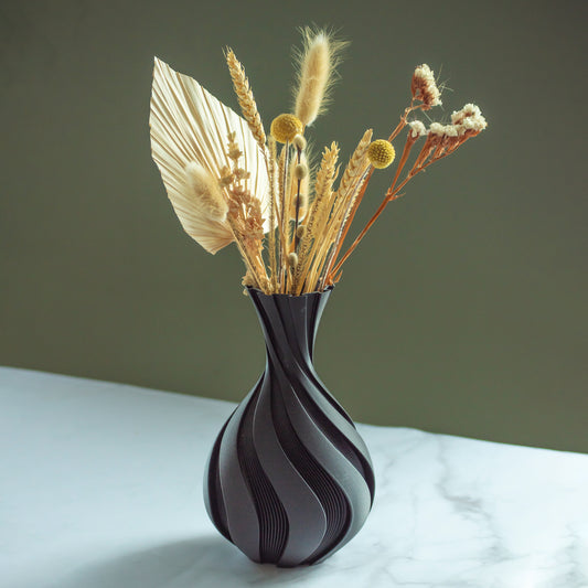 Zwarte vaas Spira met droogbloemen op marmeren blad en groene achtergrond