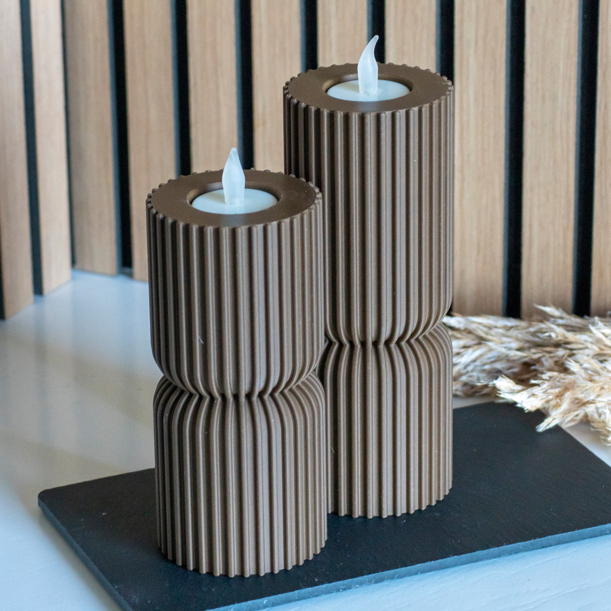 Hoge en lage waxinelichthouders als kandelaar in kleur donkerbruin voor LED lichtjes op witte tafel en houten achtergrond