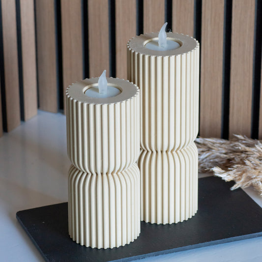 Hoge en lage waxinelichthouders als kandelaar in kleur beige voor LED lichtjes op witte tafel en houten achtergrond