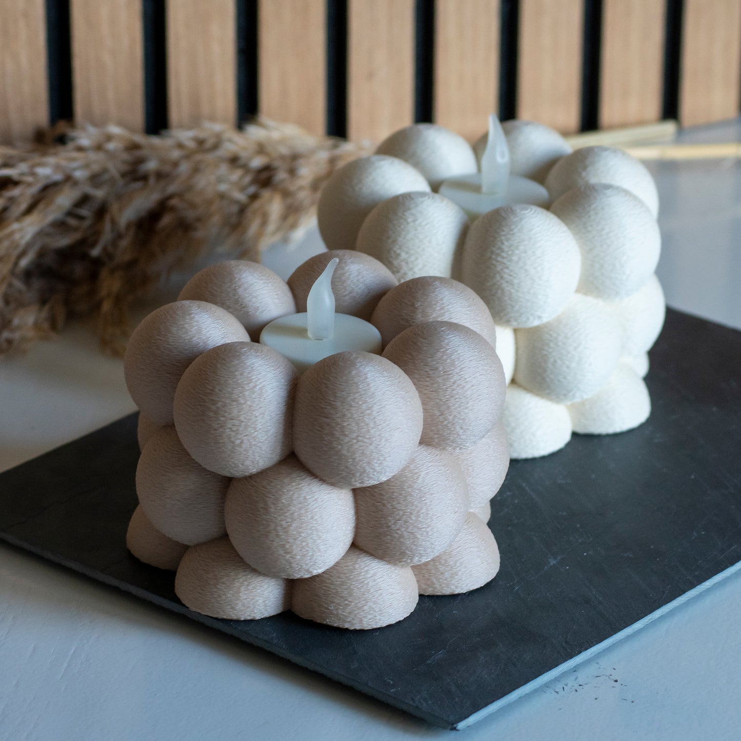 Waxinelichthouders met bubbelpatroon in beige en latte voor LED lichtjes op witte tafel en houten achtergrond