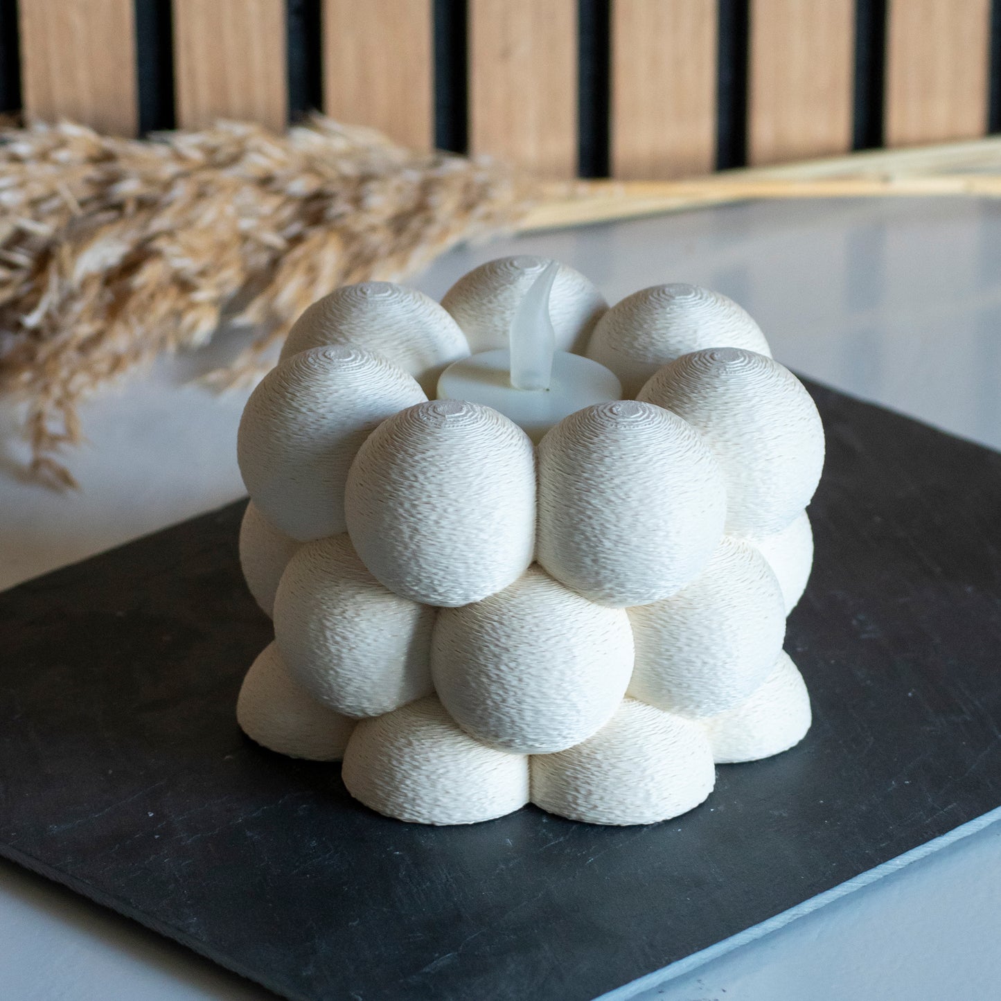 Waxinelichthouder met bubbelpatroon in kleur beige voor LED lichtjes op witte tafel en houten achtergrond