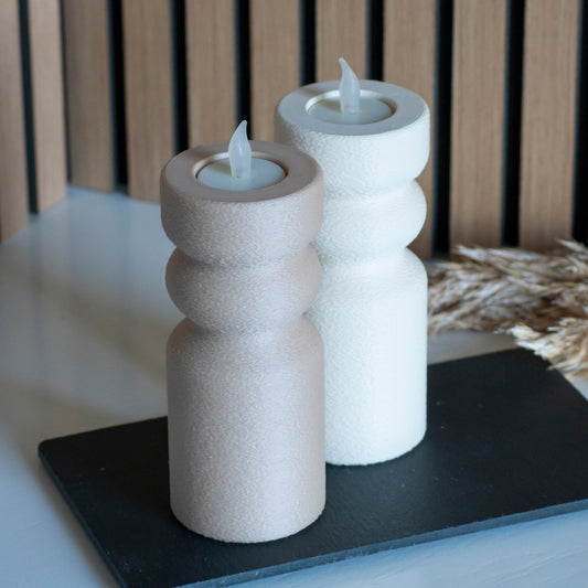 Waxinelichthouders als kandelaar in latte en beige voor LED lichtjes op witte tafel en houten achtergrond