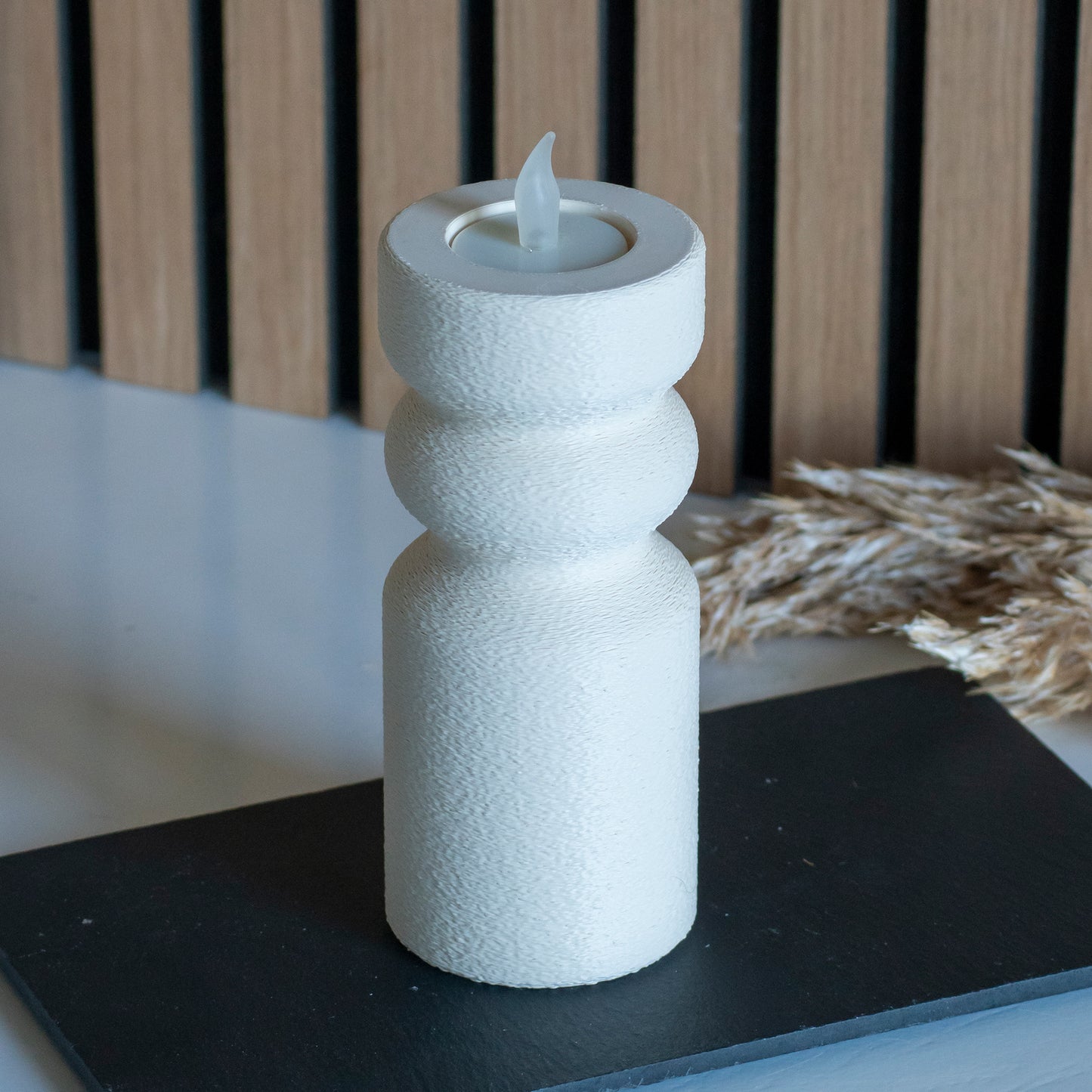 Waxinelichthouder als kandelaar in kleur beige voor LED lichtjes op witte tafel en houten achtergrond