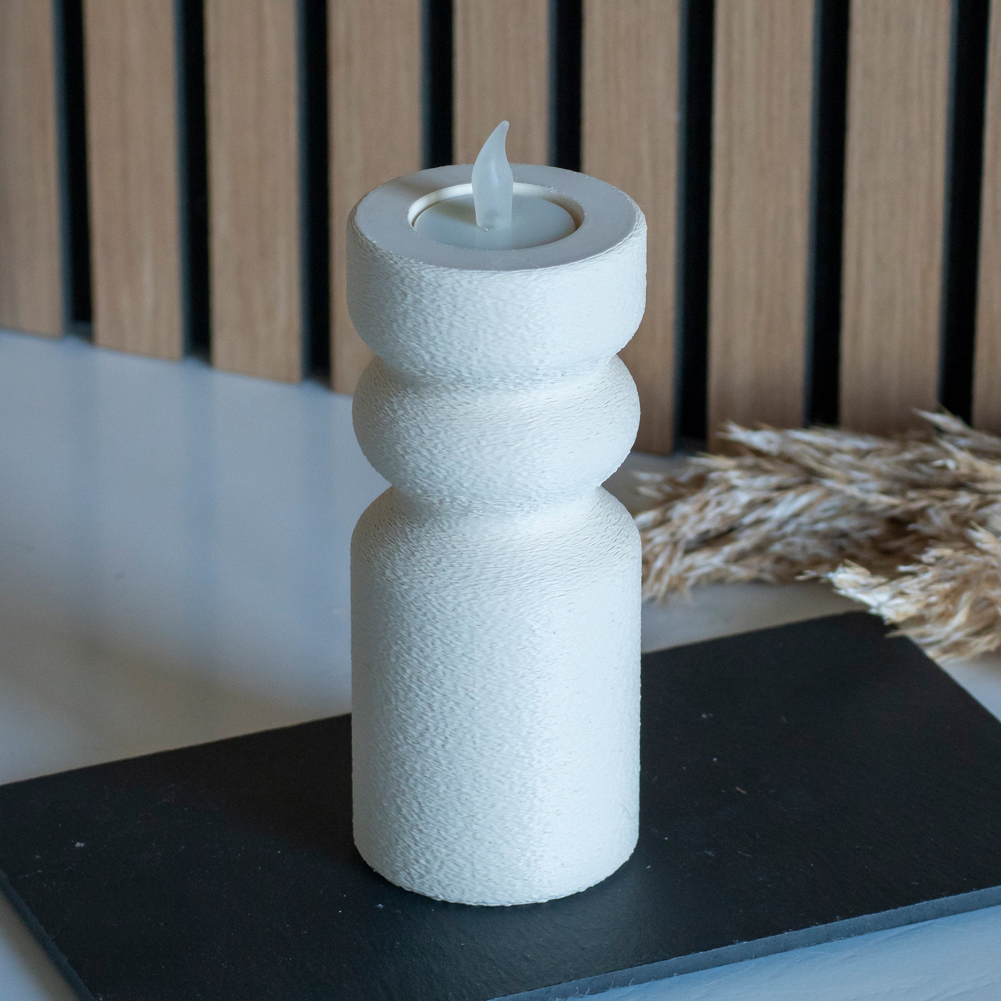 Waxinelichthouder als kandelaar in kleur beige voor LED lichtjes op witte tafel en houten achtergrond