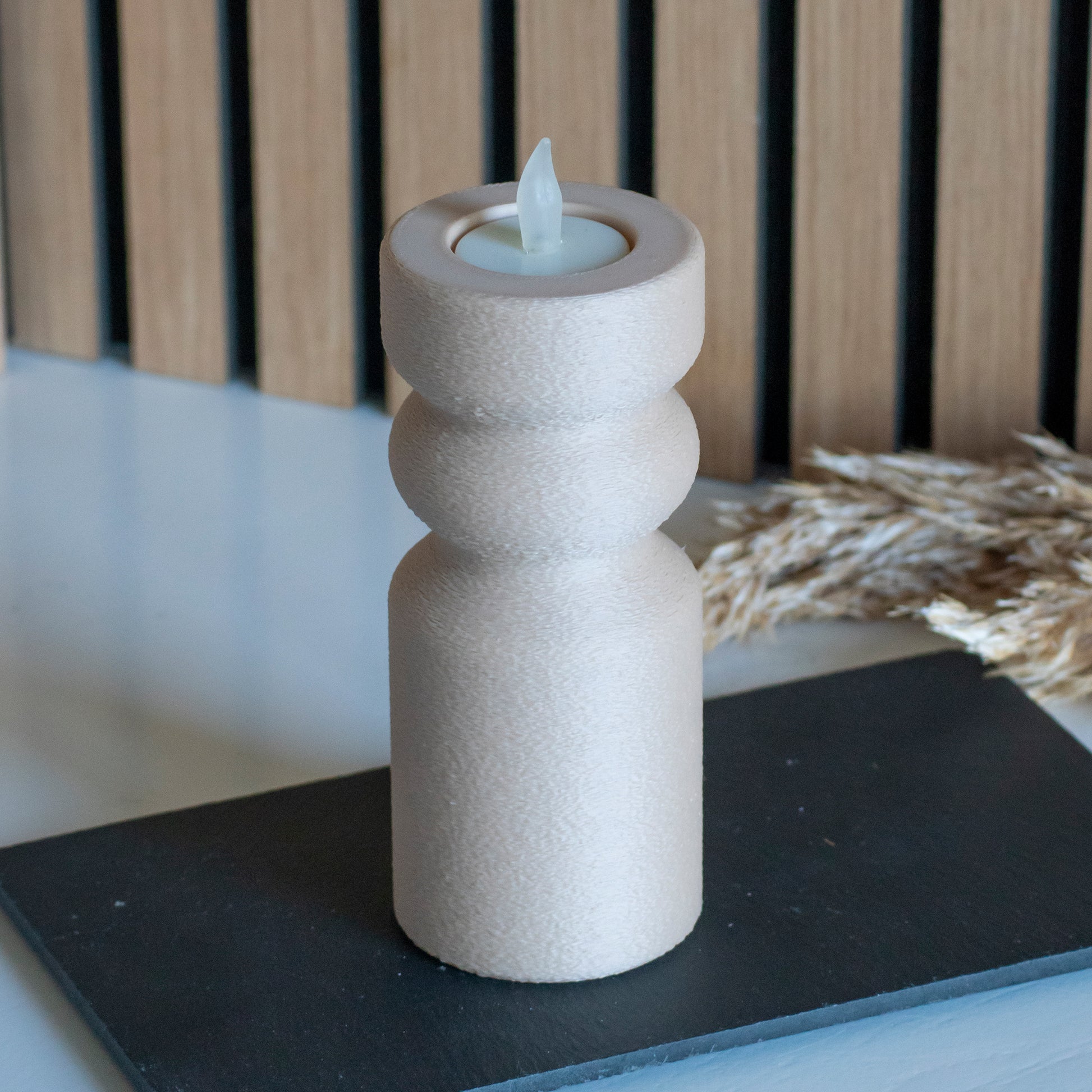 Waxinelichthouder als kandelaar in kleur latte voor LED lichtjes op witte tafel en houten achtergrond